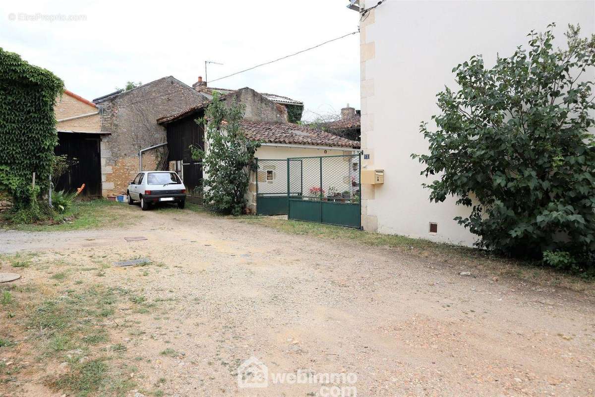 Une allée mène au portail vert de la cour. - Maison à CHAUVIGNY